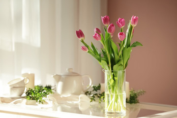 Vase with beautiful tulips on glass table
