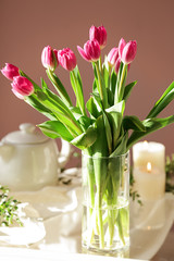 Vase with beautiful tulips on glass table