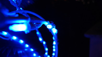 Metal white structure covered with shiny electric blue Christmas fairy lights in a black background . copy space