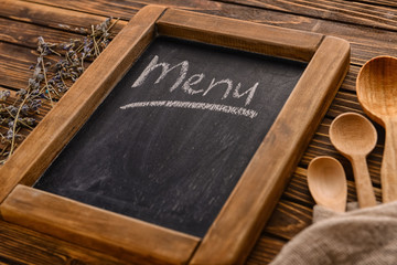 Text MENU written with chalk on board, closeup