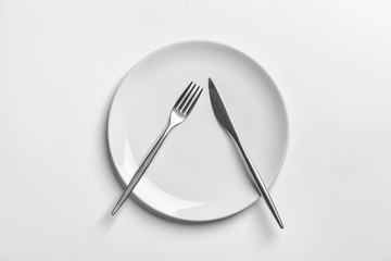 Plate with cutlery on white background