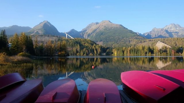 Picturesque autumn view of lake Strbske pleso in High Tatras National Park, Slovakia. Row of red wooden boats and high mountains on background