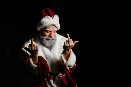 Portrait of a bad brutal mature Santa Claus showing middle finger signs, isolated on black background