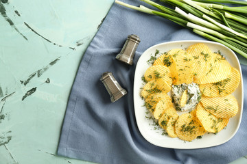 Tasty crispy potato chips with sour cream and dill on plate