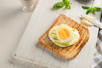 Delicious toast with cream cheese and boiled egg on wooden board