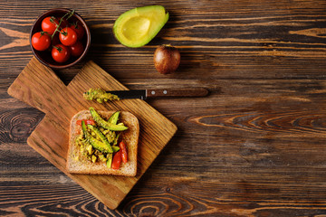 Tasty toasted bread with avocado on wooden table