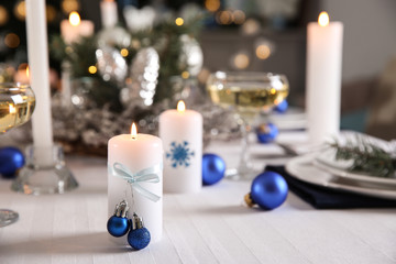Burning candle on beautiful table setting for Christmas dinner