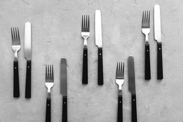 Knives and forks on grey background, flat lay
