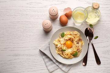 Fototapeta na wymiar Plate with delicious pasta carbonara on white wooden table, top view
