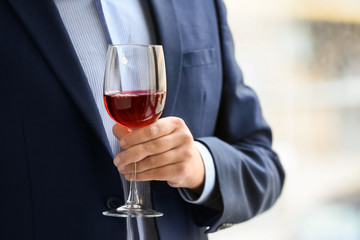 Businessman drinking wine near window, closeup