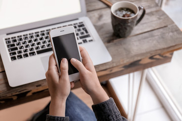 Woman with mobile phone and laptop sitting at table