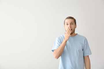 Shocked young man on light background