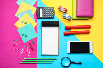 Mobile phone and school stationery on color background, top view