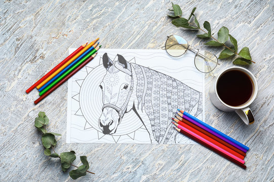 Adult anti stress coloring picture, pencils and cup of coffee on table, top view