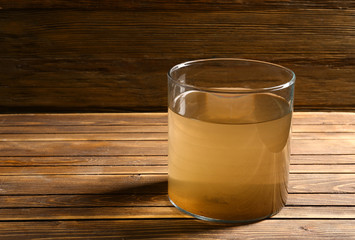 Glass of dirty water on wooden table