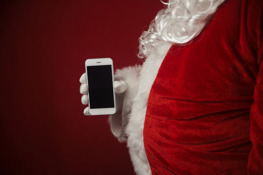 Santa Claus using working on mobile phone. Closeup image of modern communication technology. Telephone call, sending text message, taking photography and filming video during joyful happy time.