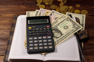 Notepad with dollars, pencil and calculator on wooden desk. Financial planning concept