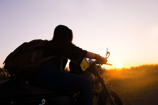 Silhouette of young woman drive with motorbike on street, enjoying freedom and active lifestyle, having fun on a bikers tour.
