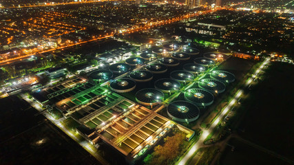 Aerial view water treatment plant at night with cityscape for environment concept.