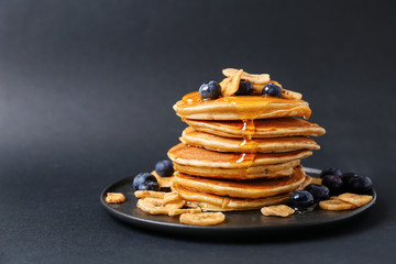Stack of hot tasty pancakes with honey, blueberries and banana slices on plate