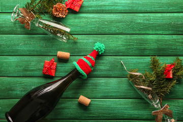 Glasses and bottle of champagne with Christmas decor on color wooden background