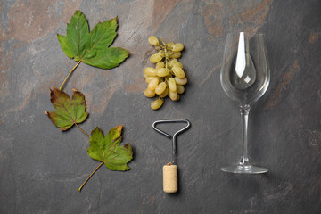 Composition with empty glass, grapes and bottle opener on grey table