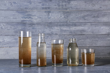 Glassware with dirty water on wooden background