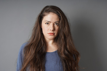 young woman with a serious look on her face - gray background with copy space