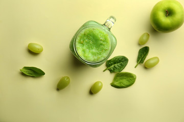 Mason jar of tasty green smoothie on color table