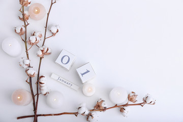 Cotton flowers, burning candles and date JANUARY, 1 on white background