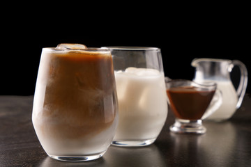 Glass of tasty cold coffee and ingredients on dark table