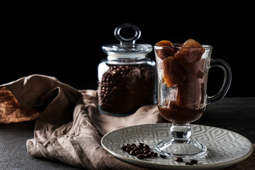 Glass cup with coffee cubes on dark table
