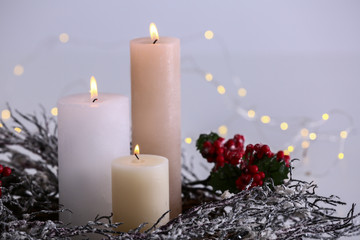 Beautiful burning candles with Christmas decorations on light background