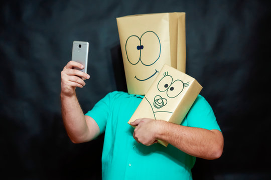 Emotion concept. A man takes a selfie on his mobile phone. In his left hand he holds a baby. On the face is a smile and an expression of joy.