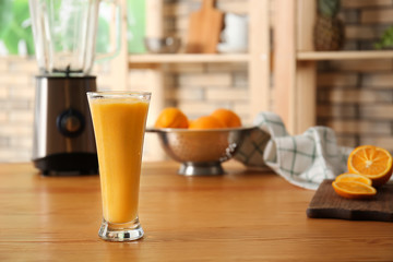 Glass of tasty orange smoothie on wooden table