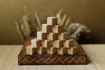 Cubes of brown sugar on the kitchen table. Rustic still life with wooden and glass utensils.