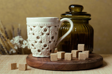 Cubes of brown sugar on the kitchen table. Rustic still life with wooden and glass utensils.