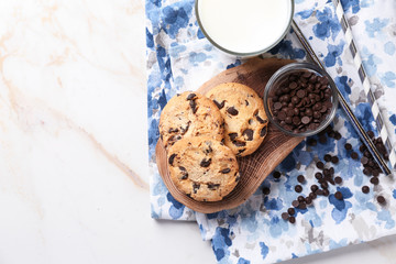 Tasty cookies, bowl with chocolate chips and glass of milk on table