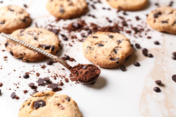 Tasty cookies with chocolate chips and spoon of cocoa powder on table