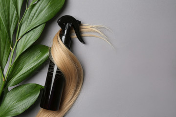 Spray bottle with cosmetic for hair on grey background, top view