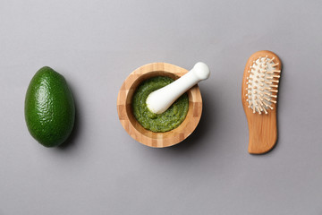 Flat lay composition with fresh avocado and natural cosmetic for hair on grey background