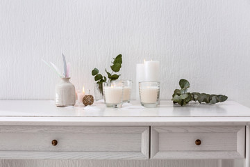 Beautiful composition with burning candles on table near white wall