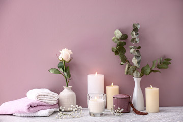 Beautiful composition with burning candles on table near color wall