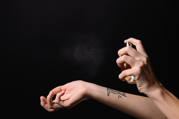 Woman with bottle of perfume on dark background