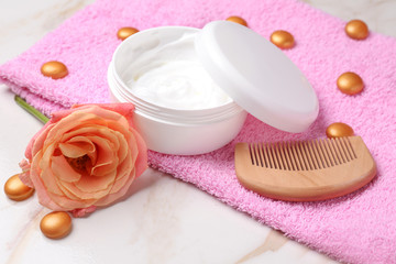 Comb and jar with cosmetic for hair on table