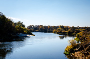 Obraz premium Riverbed surrounded by trees on one side. Sandy banks of the river