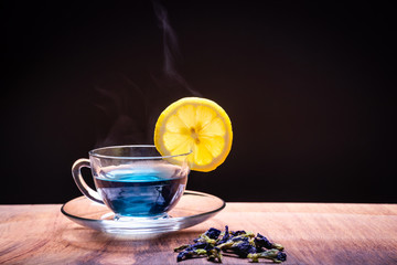 Cup of Butterfly pea flower tea with lemons on wooden background. Health drink concept.