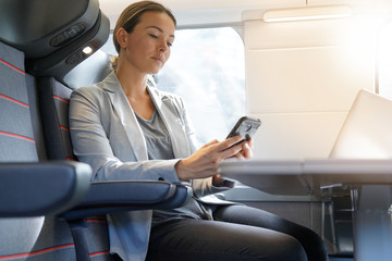 Businesswoman in first class on train looking at cellphone