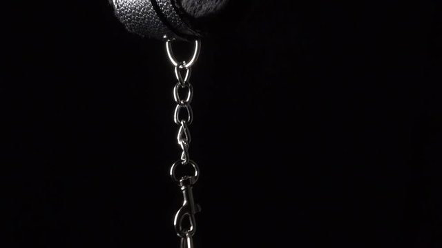 Closeup of black leather handcuffs on the black background