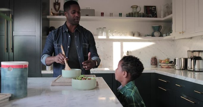 African American boy helping father prepare healthy meal in kitchen